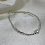 CAELLIA freshwater pearl bracelet on a 925 sterling silver chain resting on white fabric.
