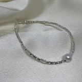CAELLIA freshwater pearl bracelet on a 925 sterling silver chain resting on white fabric.