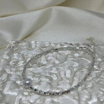 CAELLIA freshwater pearl and 925 sterling silver bracelet on a textured glass surface.