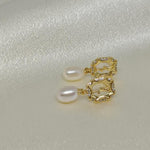 CAELLIA freshwater pearl and gold-plated rose earrings on a white satin background.