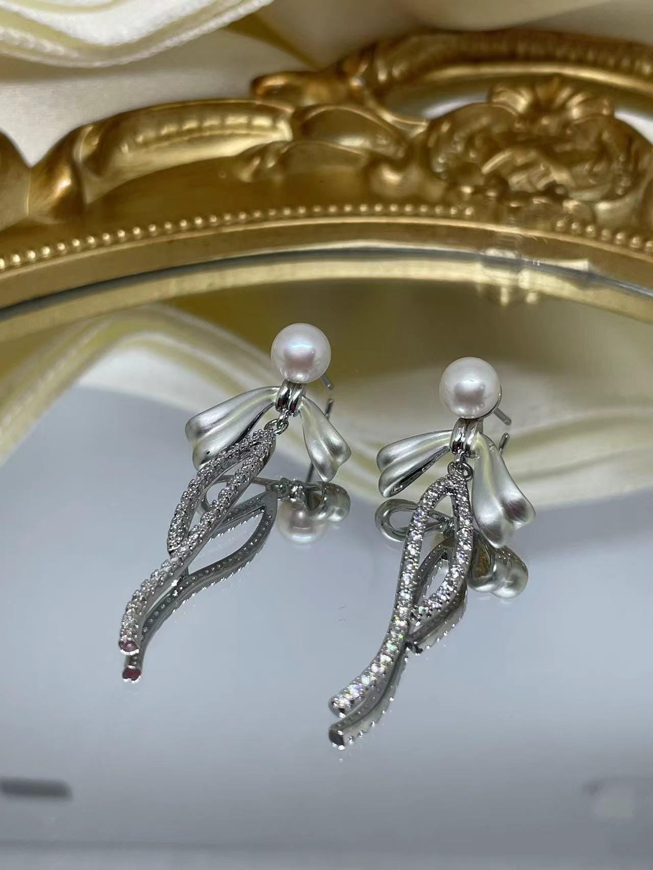 CAELLIA sterling silver dangle earrings featuring a pearl bow design with pavé accents.