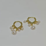 Caellia 14K gold huggie hoop earrings featuring dangling freshwater pearls.