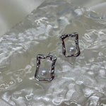 CAELLIA silver stud earrings featuring a lustrous freshwater pearl inside a textured square frame.