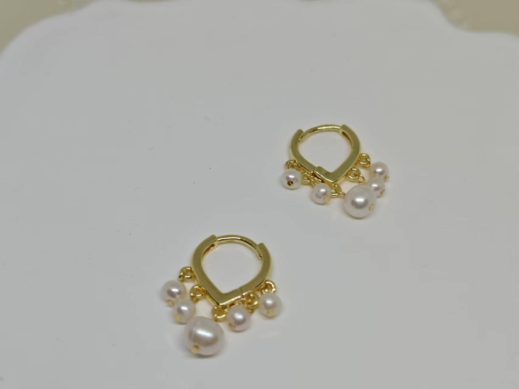 Caellia 14K gold huggie hoop earrings featuring delicate dangling freshwater pearls.