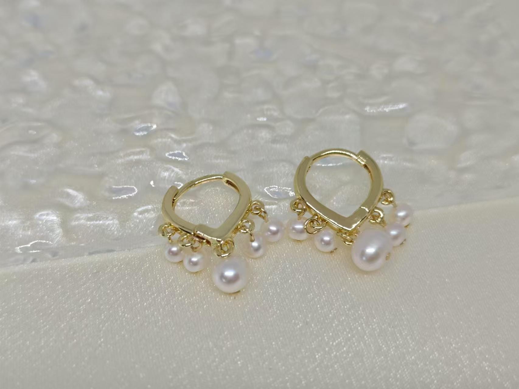 Caellia 14K gold huggie hoop earrings featuring dangling freshwater pearls.