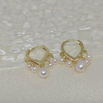 Caellia 14K gold huggie hoop earrings featuring dangling freshwater pearls.