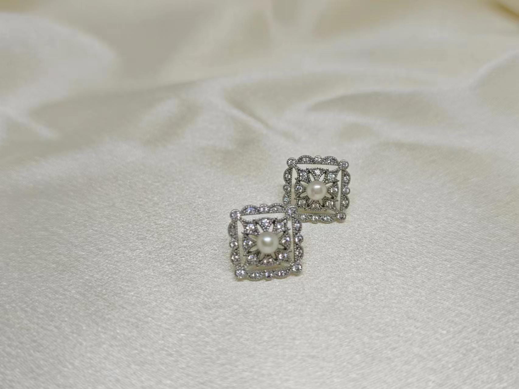 CAELLIA sterling silver square stud earrings featuring a central freshwater pearl and diamond accents.