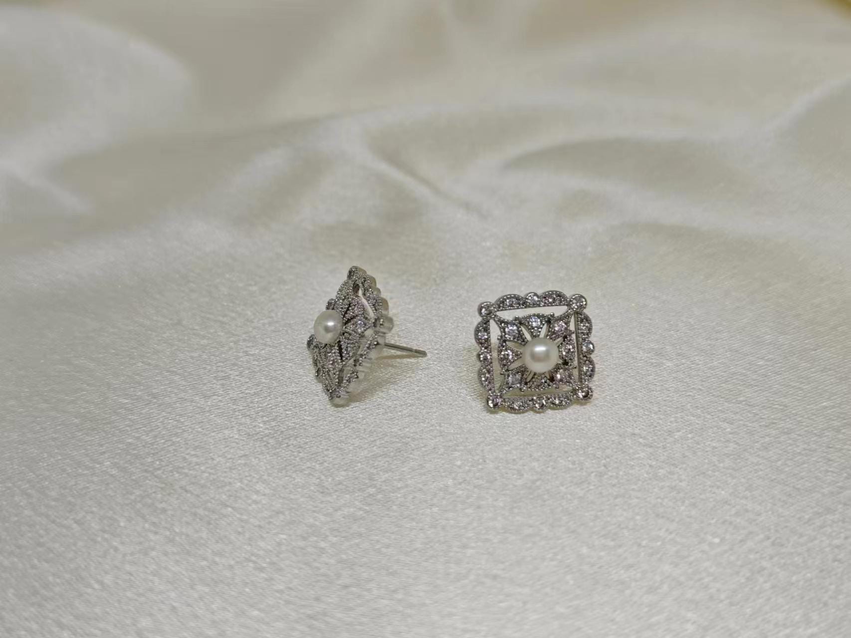 CAELLIA sterling silver square stud earrings featuring a central freshwater pearl and diamond accents.