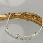 Caellia freshwater pearl necklace with silver accents resting on a gold-framed mirror.