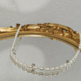 Caellia freshwater pearl necklace with silver accents resting on a gold-framed mirror.