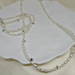 A Caellia freshwater pearl necklace with small white beads resting on a white dish.