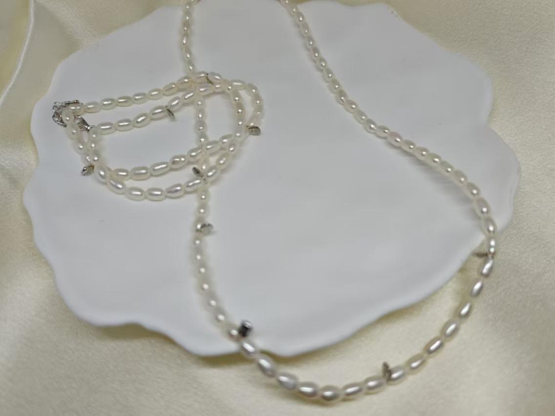 A Caellia freshwater pearl necklace with small white beads resting on a white dish.