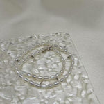 CAELLIA double wrapped freshwater pearl bracelet with sterling silver accents on a textured surface.