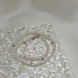 CAELLIA double wrapped freshwater pearl bracelet with sterling silver accents on a textured surface.