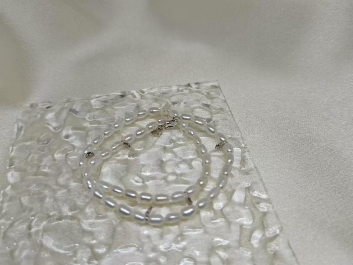 CAELLIA double wrapped freshwater pearl bracelet with sterling silver accents on a textured surface.