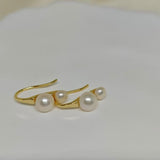 Caellia 18K gold plated stud earrings featuring two freshwater pearls on a curved gold bar.