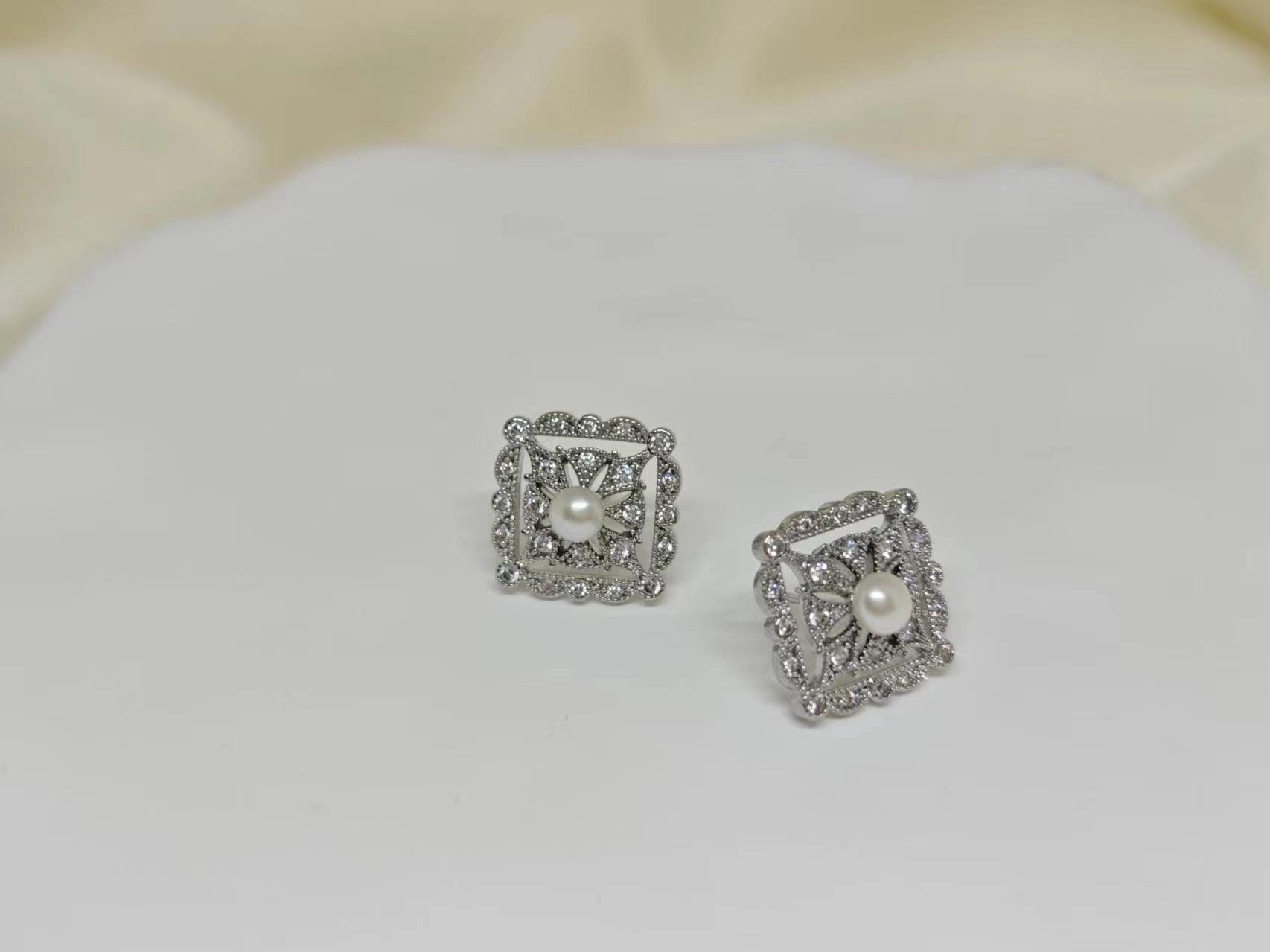CAELLIA sterling silver square stud earrings featuring a central freshwater pearl and diamond accents.