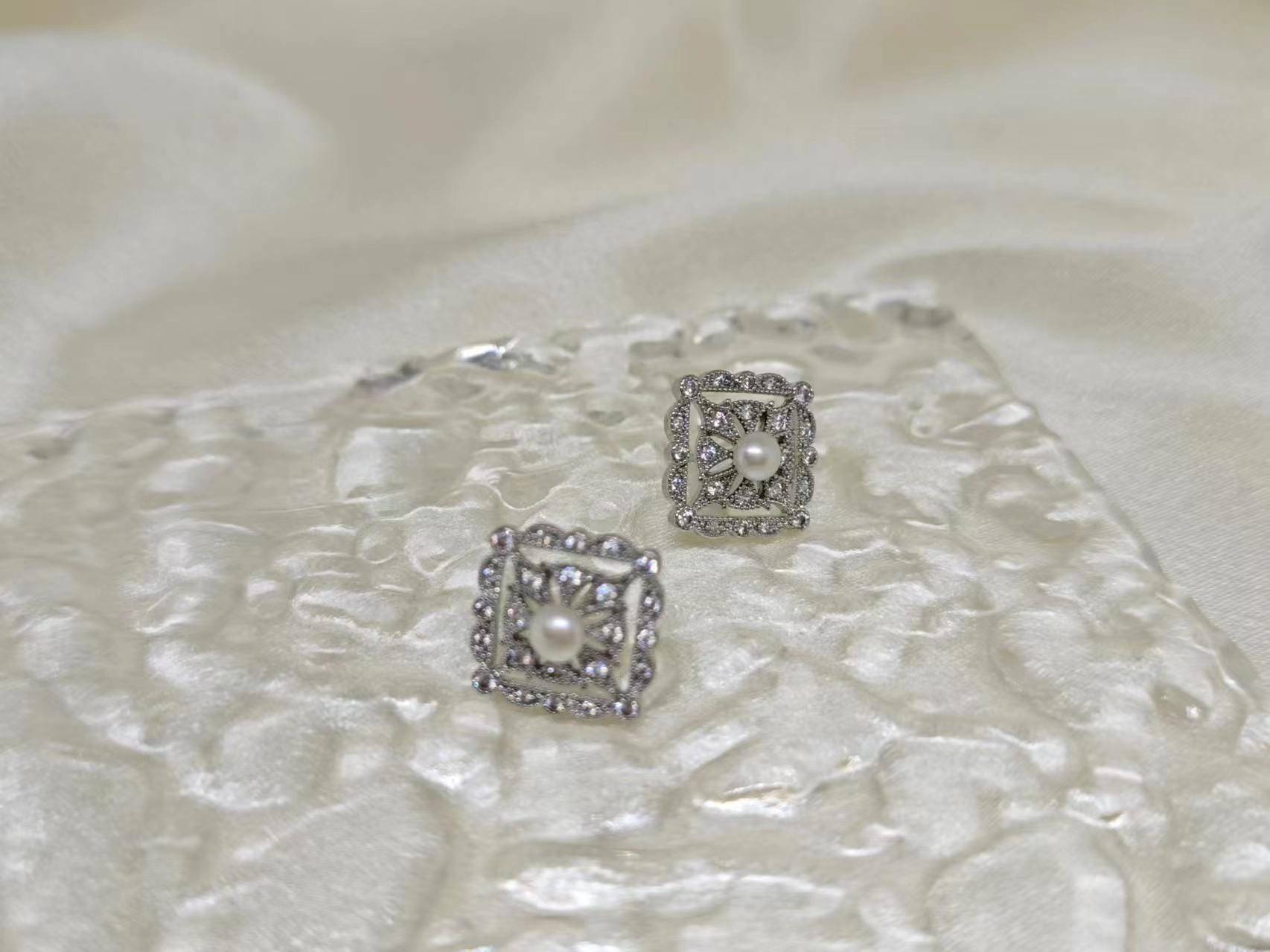 CAELLIA sterling silver square stud earrings featuring a central freshwater pearl and diamond accents.