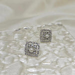 CAELLIA sterling silver square stud earrings featuring a central freshwater pearl and diamond accents.