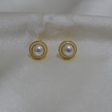 CAELLIA gold plated freshwater pearl stud earrings with a circular frame on a white fabric background.