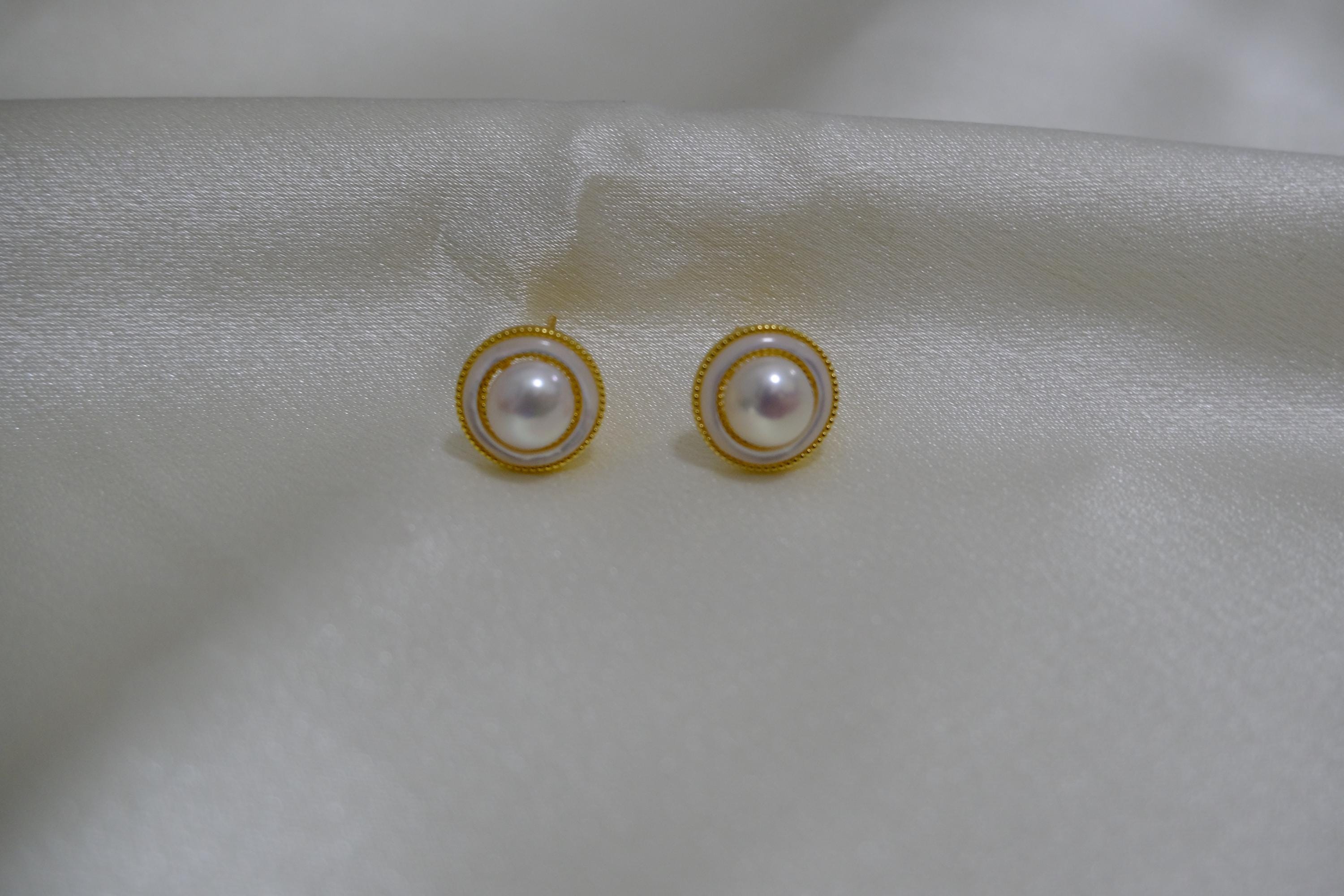 CAELLIA gold plated freshwater pearl stud earrings with a circular frame on a white fabric background.