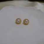CAELLIA gold plated freshwater pearl earrings featuring a lustrous pearl in a circular frame.