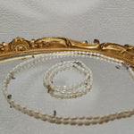 A Caellia freshwater pearl necklace with AAA grade beads displayed on a gold-rimmed mirror.