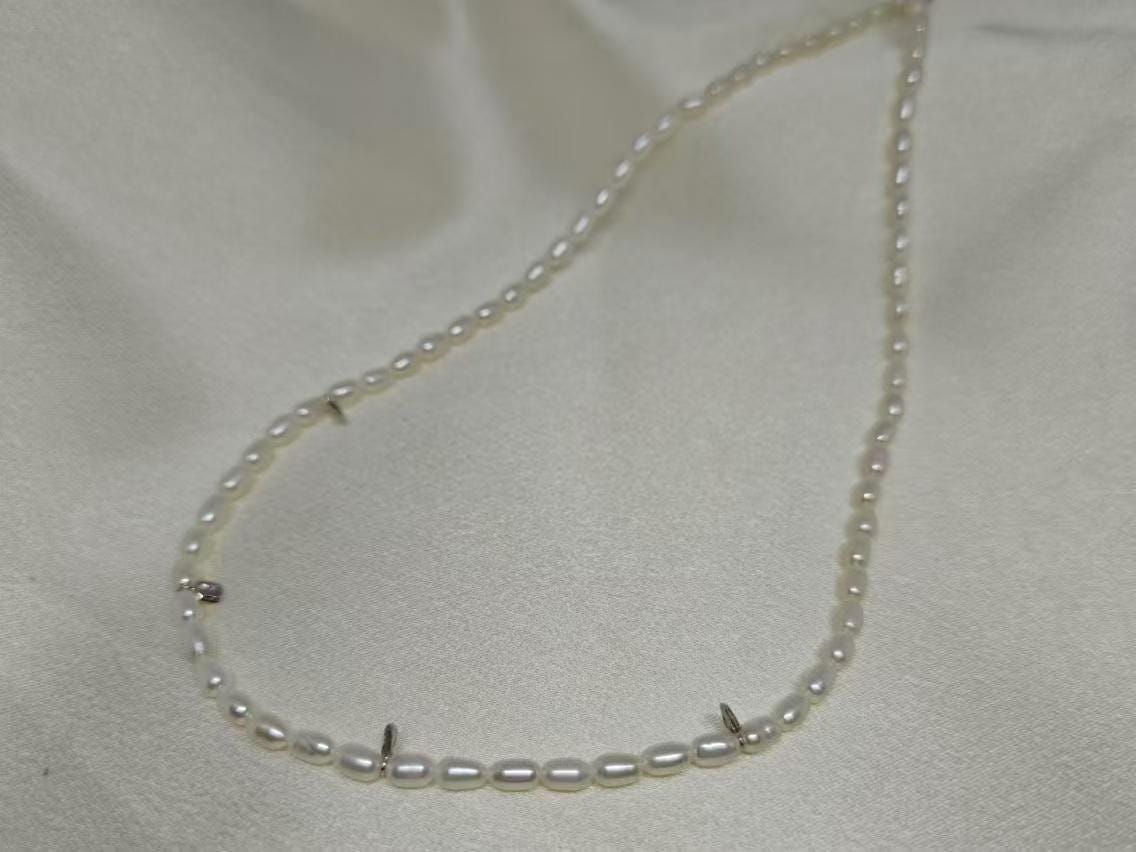 A delicate Caellia freshwater pearl necklace featuring small white beads on a silver chain.