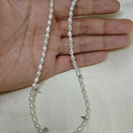A hand holding a Caellia freshwater pearl necklace with small white beads on a silk background.
