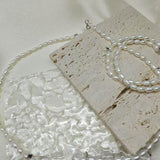 A Caellia freshwater pearl necklace with AAA grade beads resting on a textured stone surface.