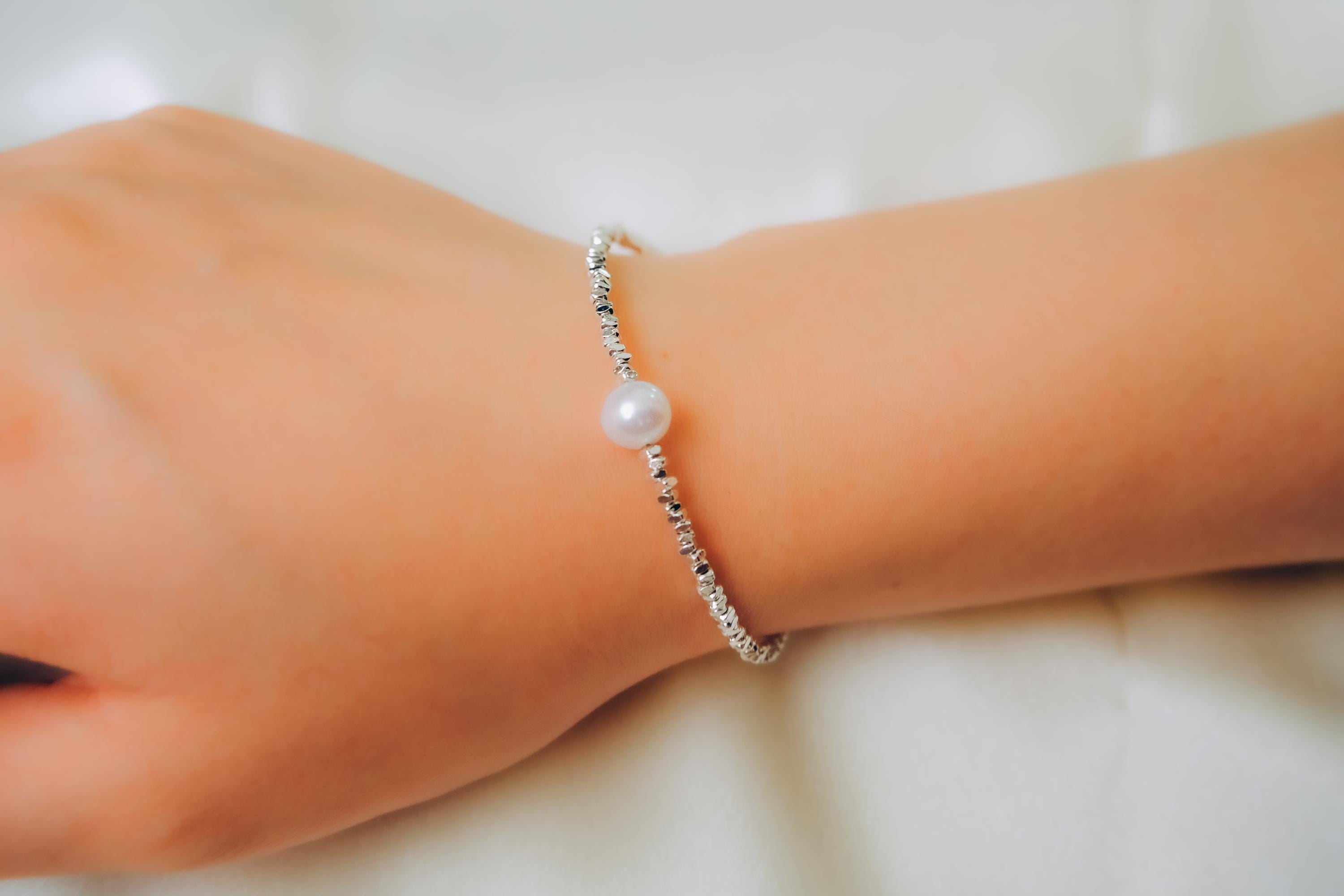 A CAELLIA freshwater pearl bracelet on a 925 sterling silver chain worn on a wrist.