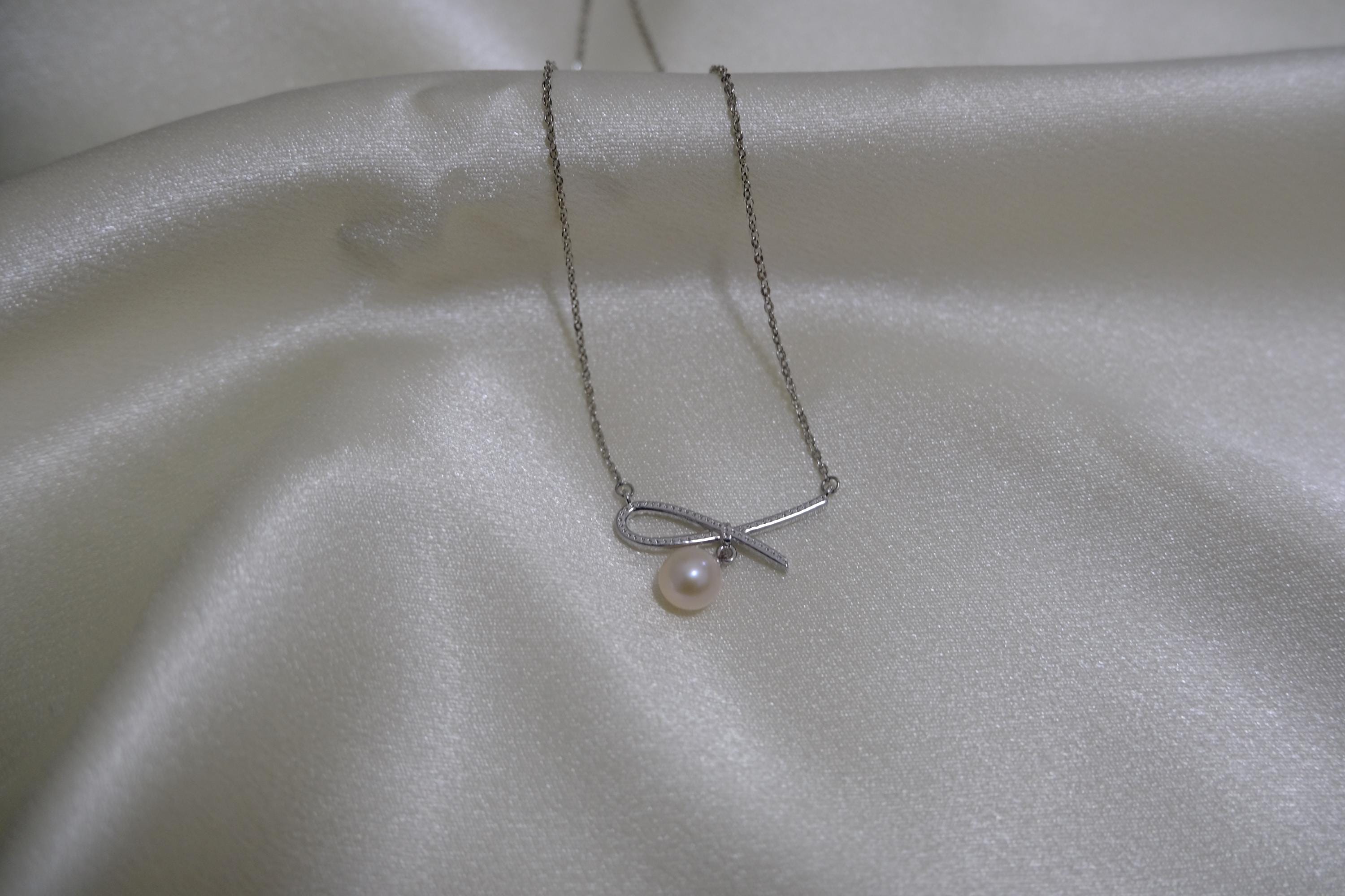 CAELLIA dainty freshwater pearl pendant necklace featuring a delicate bow design on a silver chain.
