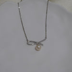 A CAELLIA dainty silver necklace featuring a bow-shaped pendant with a single freshwater pearl.