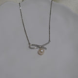 A CAELLIA dainty silver necklace featuring a bow-shaped pendant with a single freshwater pearl.