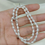 CAELLIA double wrapped freshwater pearl bracelet with sterling silver accents held in a hand.
