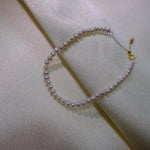 CAELLIA freshwater pearl bracelet with gold plated sterling silver hardware on white fabric.