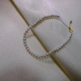 CAELLIA freshwater pearl bracelet with gold plated sterling silver hardware on white fabric.