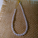 CAELLIA freshwater pearl bracelet with gold plated sterling silver hardware on a burlap background.