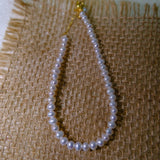CAELLIA freshwater pearl bracelet with gold plated sterling silver hardware on a burlap background.