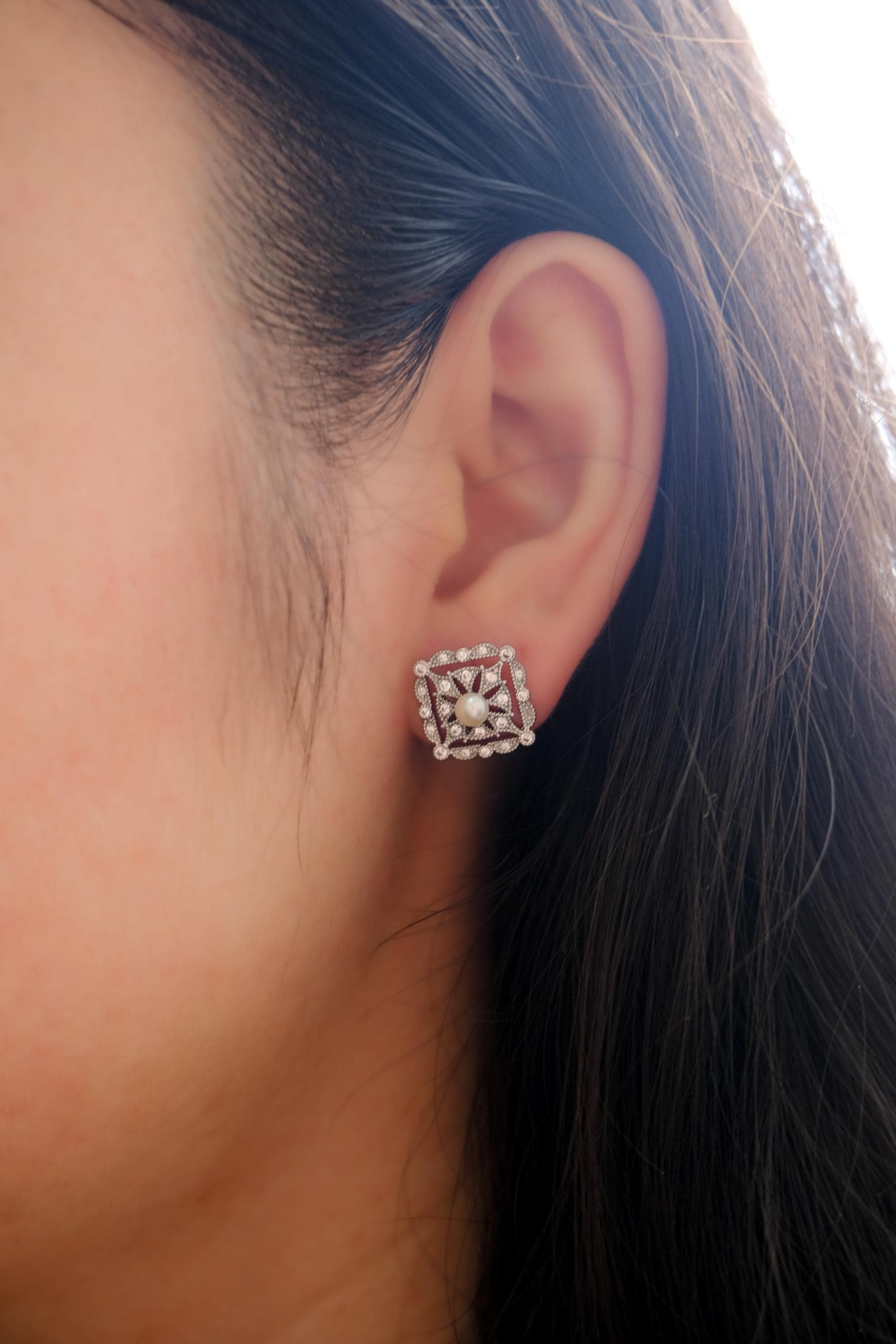 A person wears a CAELLIA sterling silver square stud earring featuring a central freshwater pearl.