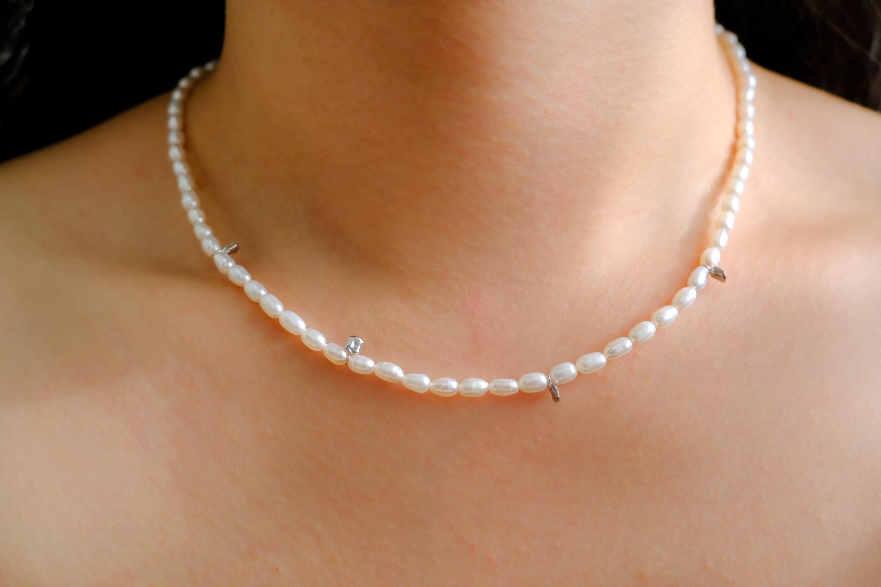 A Caellia freshwater pearl bead necklace with small silver accents worn around the neck.