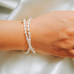 A CAELLIA double wrapped freshwater pearl bracelet with sterling silver accents on a wrist.