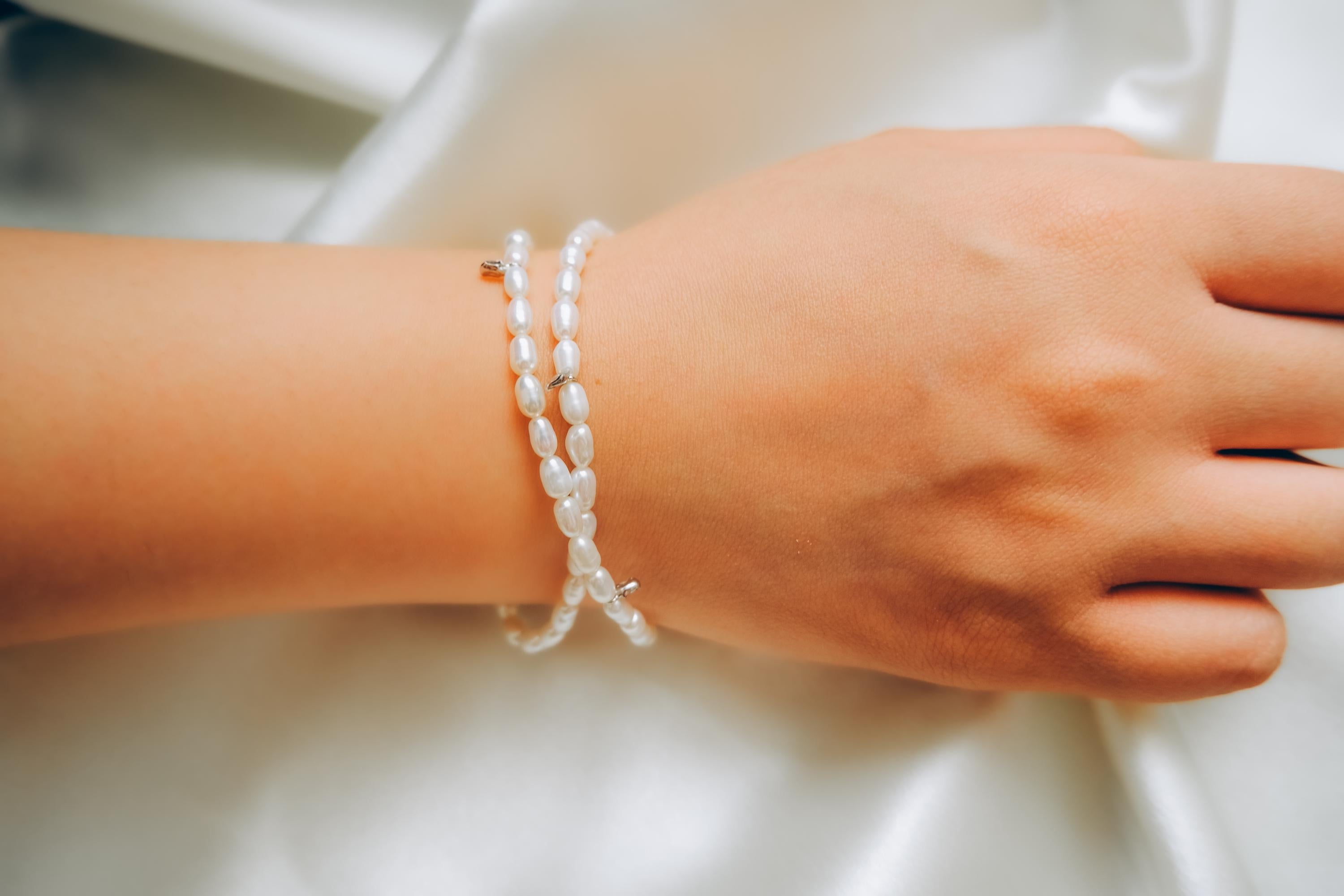 A CAELLIA double wrapped freshwater pearl bracelet with sterling silver accents on a wrist.