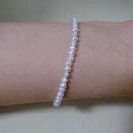 A CAELLIA freshwater pearl bracelet worn on a wrist, featuring small, luminescent white pearls.