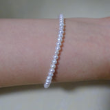 A CAELLIA freshwater pearl bracelet worn on a wrist, featuring small, luminescent white pearls.