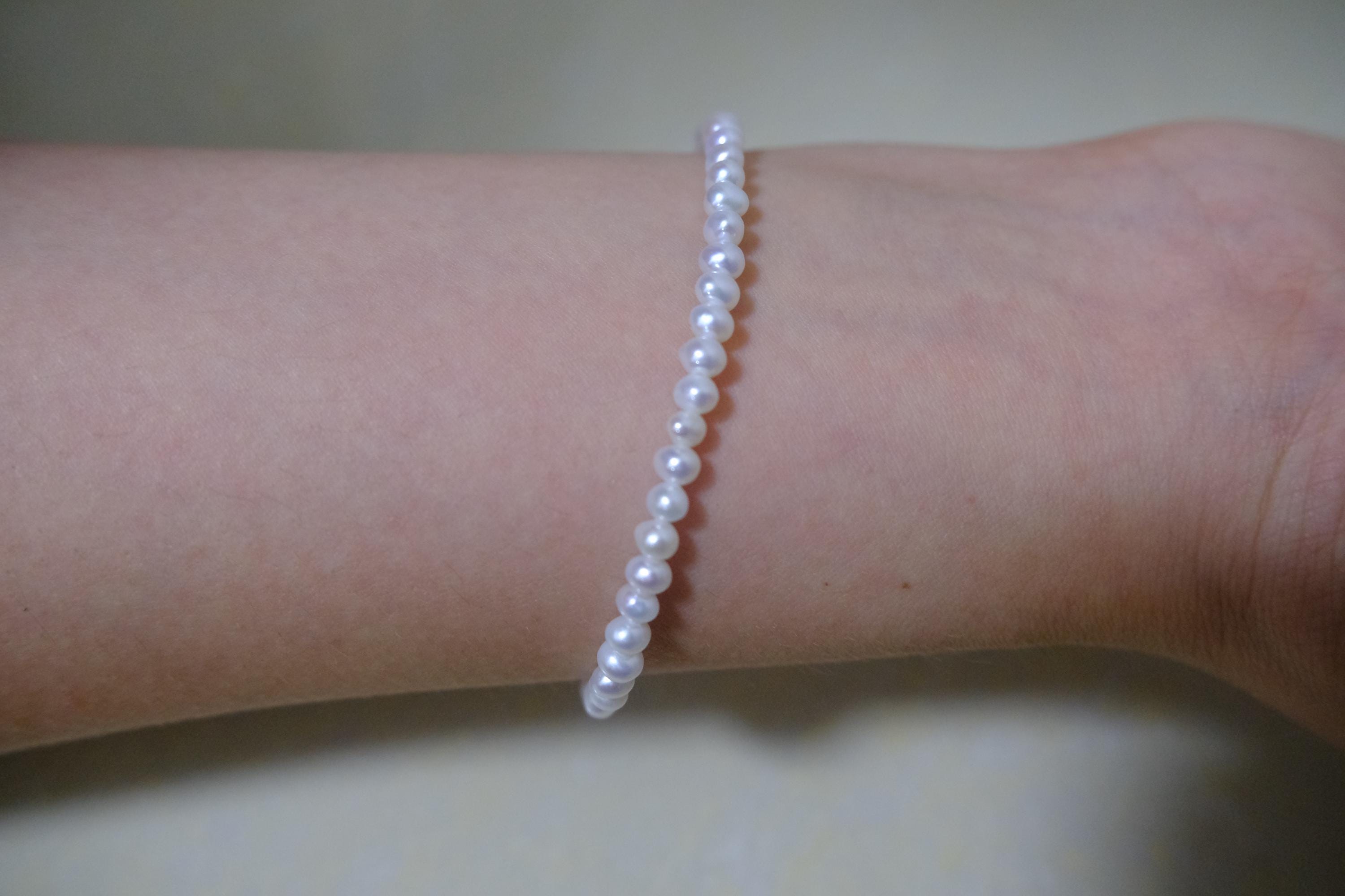 A CAELLIA freshwater pearl bracelet worn on a wrist, featuring small, luminescent white pearls.