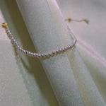 CAELLIA freshwater pearl bracelet with gold plated sterling silver hardware on draped fabric.