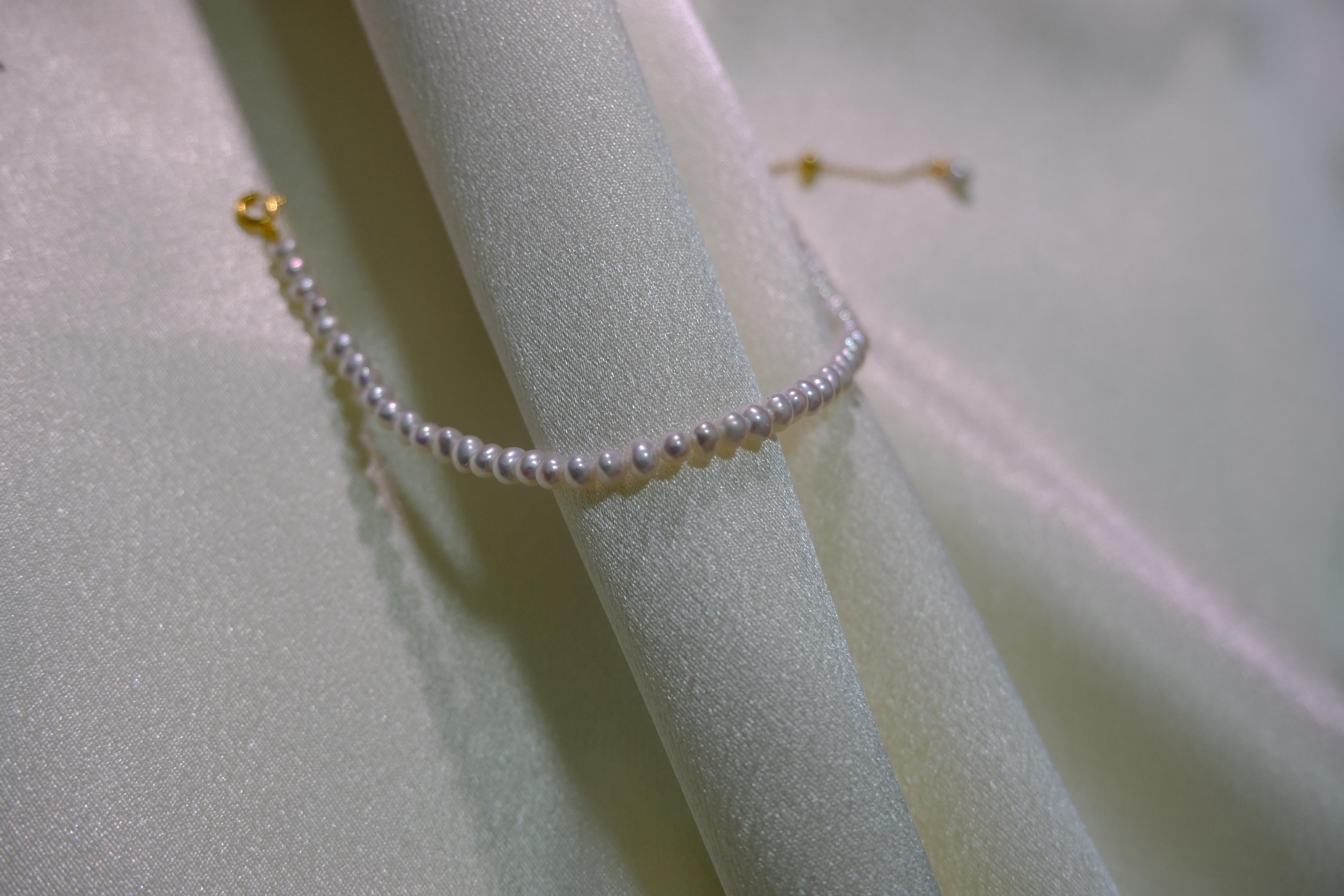 CAELLIA freshwater pearl bracelet with gold plated sterling silver hardware on draped fabric.