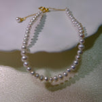 CAELLIA freshwater pearl bracelet with gold plated sterling silver hardware on a white surface.