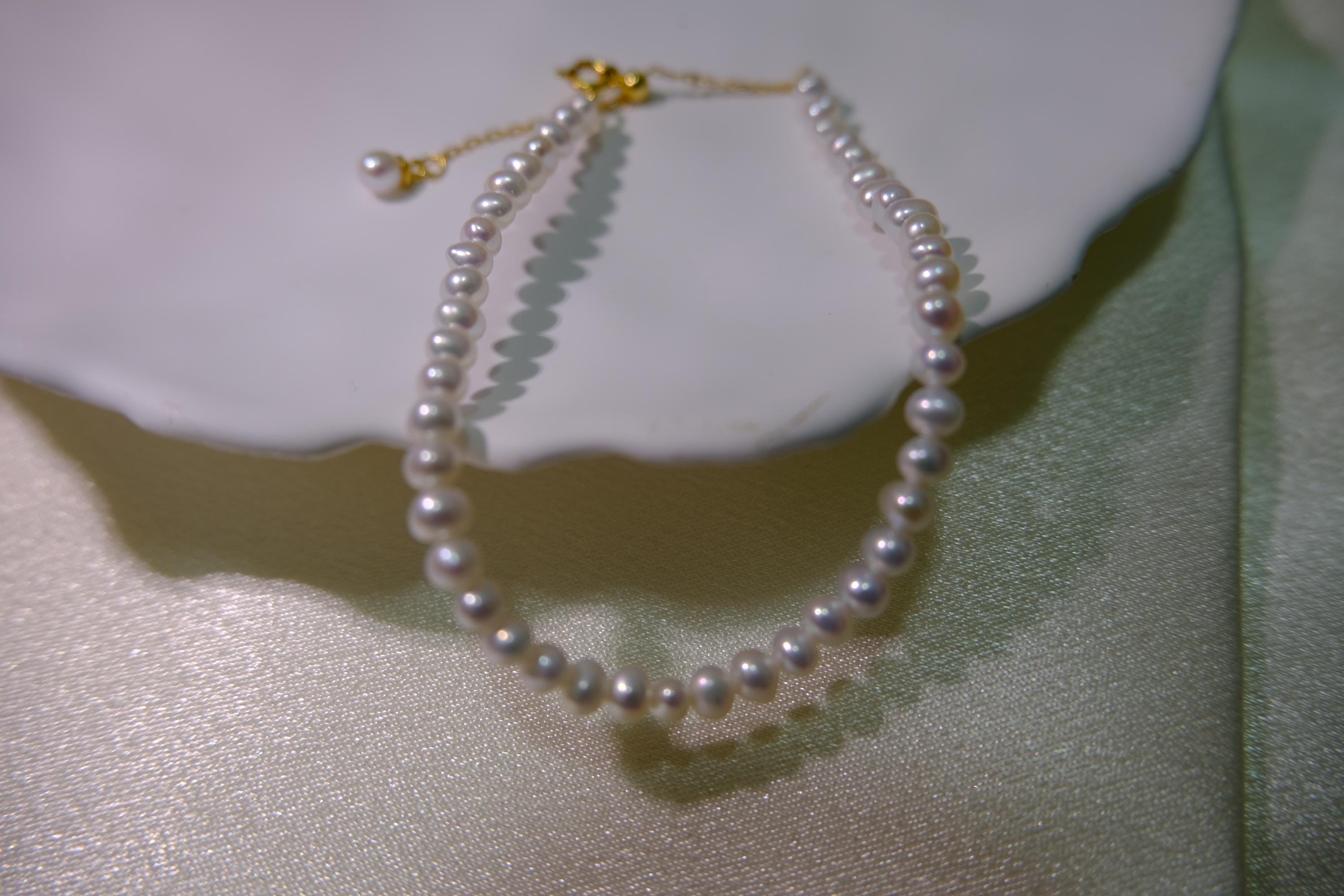 CAELLIA freshwater pearl bracelet with gold plated sterling silver hardware on a white surface.
